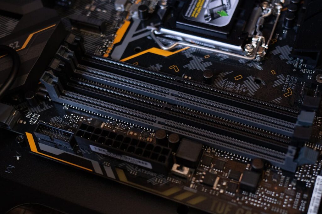pexels-photo-2582932 Detailed view of a computer motherboard showcasing RAM slots and electronic components.